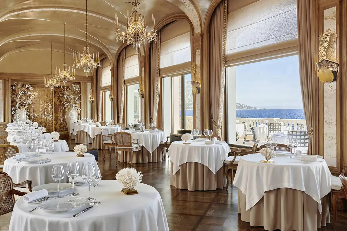 Formal dining room with arched windows, crystal chandeliers, and sea views