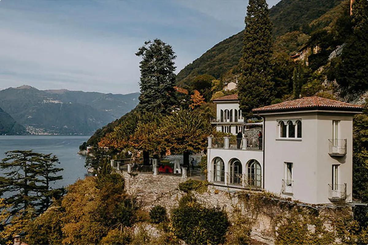 Historic villa on lakeside bluff with mountain backdrop and autumn foliage