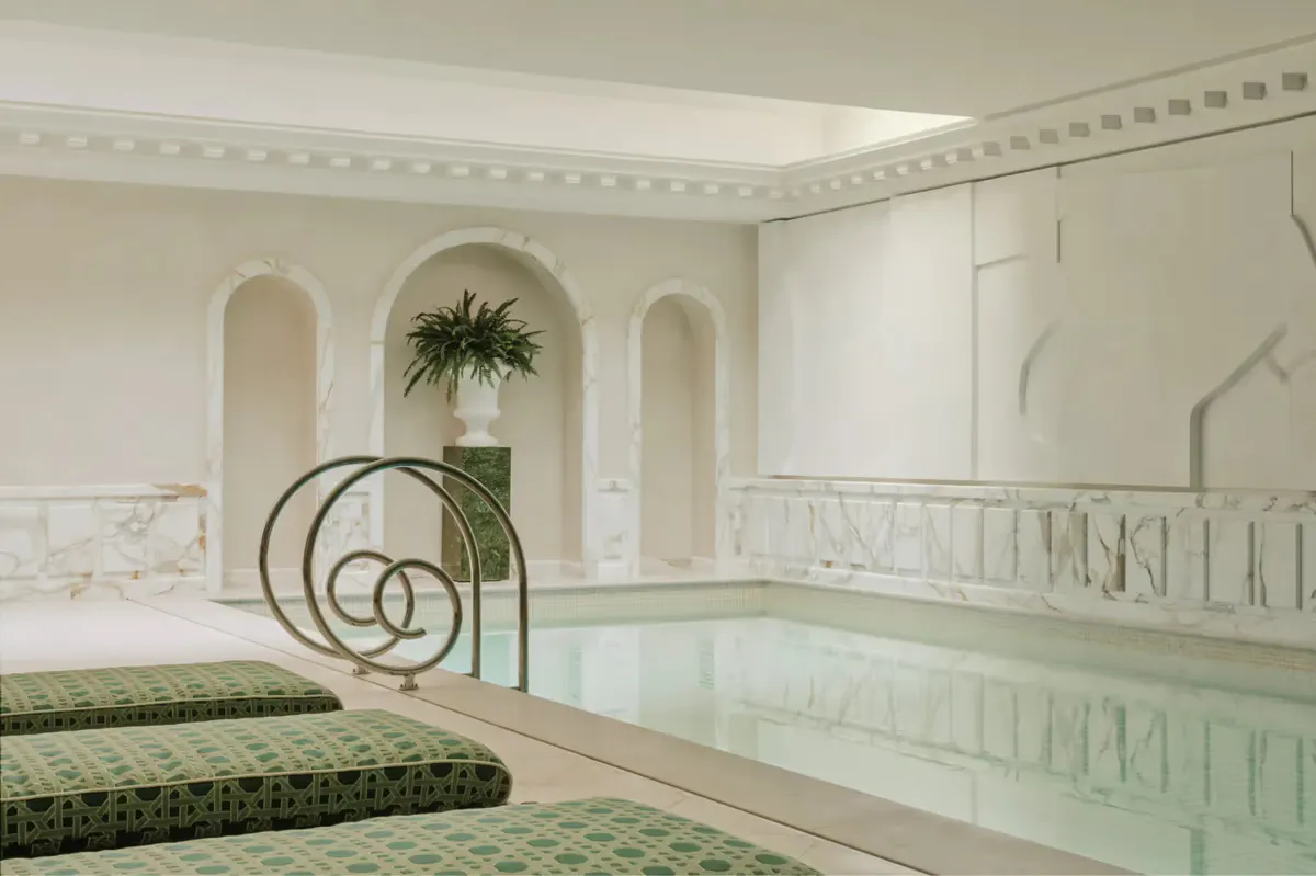 Spa facility with pale tile pool, arched architectural detail, and potted plants