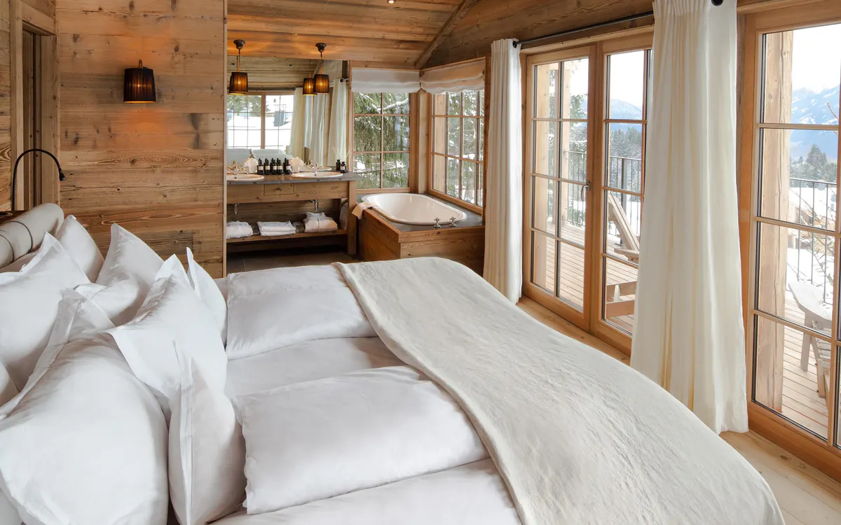 Wooden bedroom with white bedding and glass doors opening to a terrace