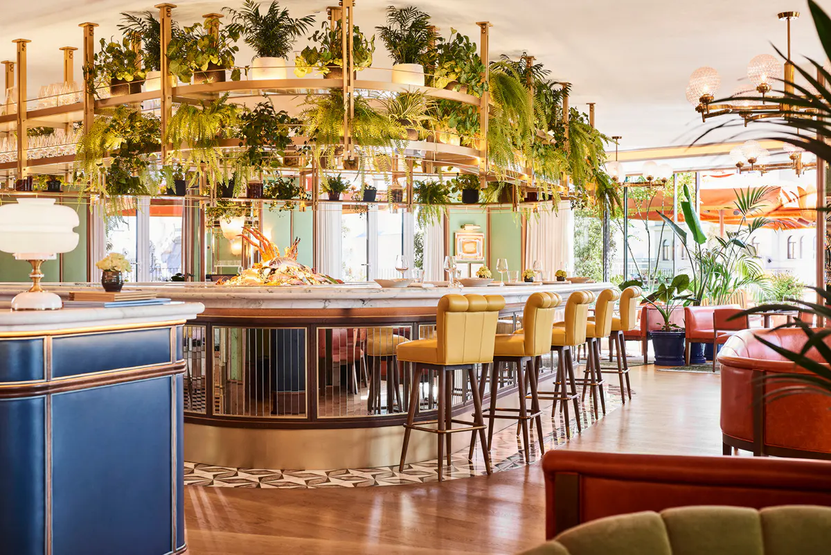 Bar and lounge with green and gold decor, living plant wall, wood paneling, and cocktail seating