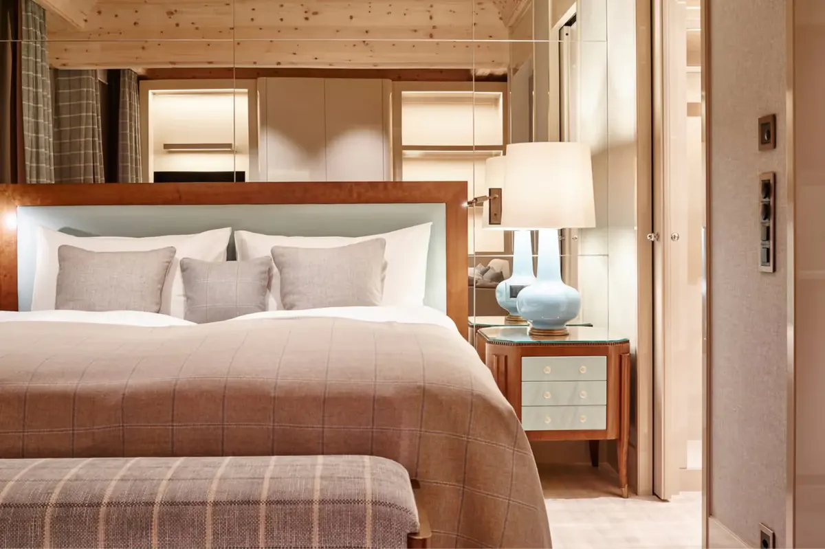 A bedroom with wood-paneled ceiling and king bed in warm neutral tones