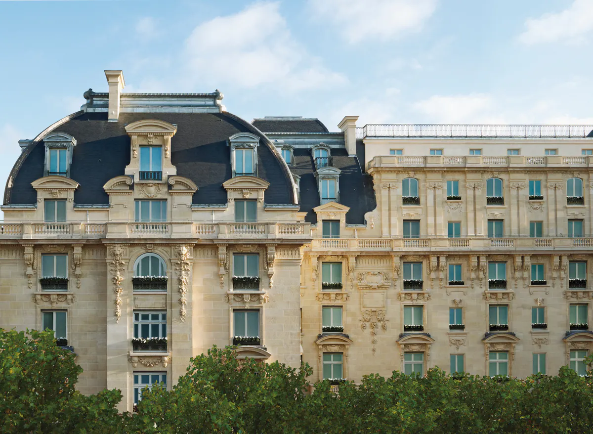 Mansard roofs and neoclassical stonework of a Haussmannian facade under bright daylight