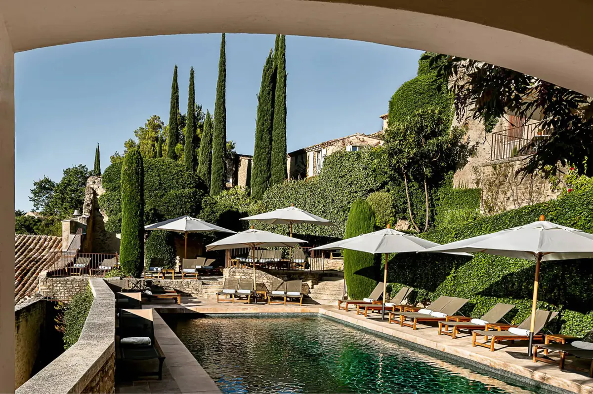 A loggia framing the pool terrace, cypress trees, and distant hills under blue sky