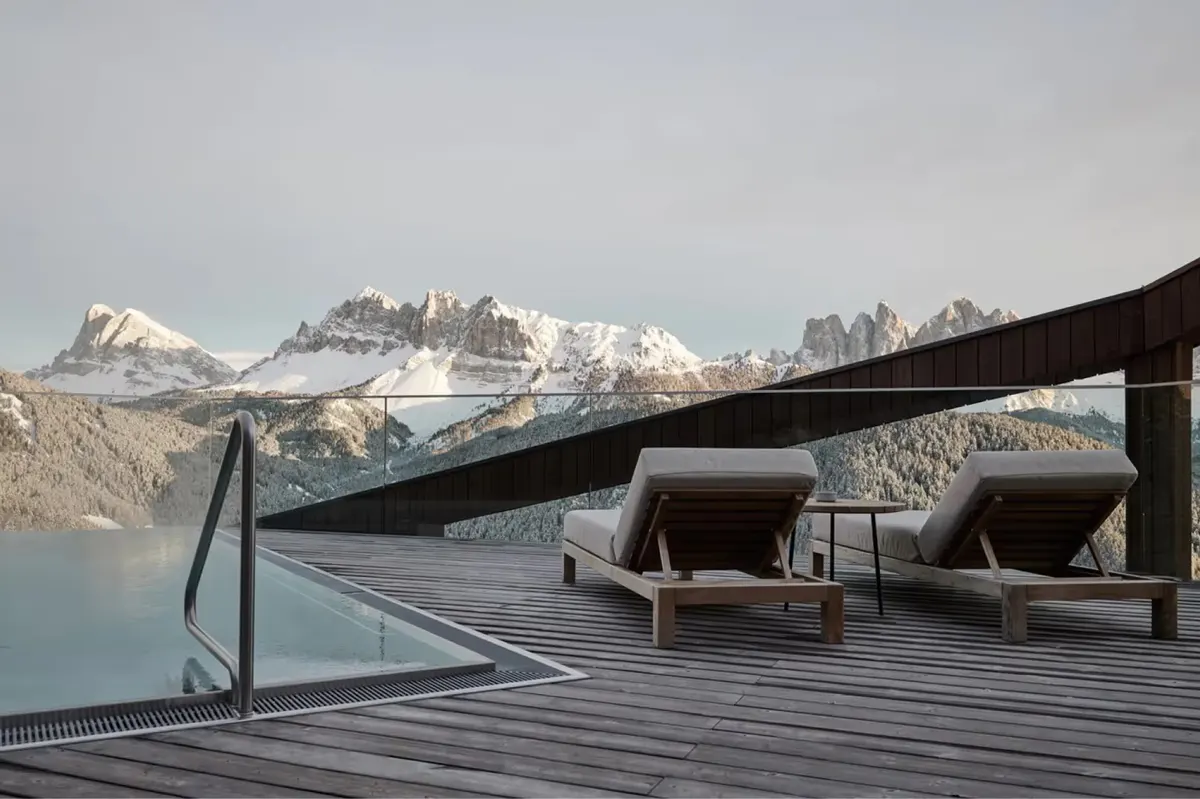 A guest area with floor-to-ceiling windows, light wood furnishings, and expansive mountain vistas