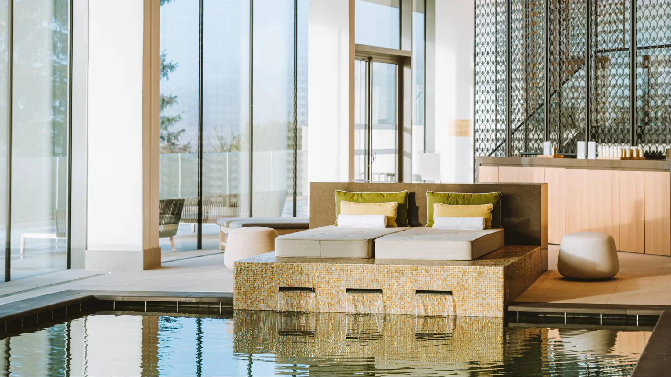 A modern spa suite with indoor pool and floor-to-ceiling windows overlooking vineyard views