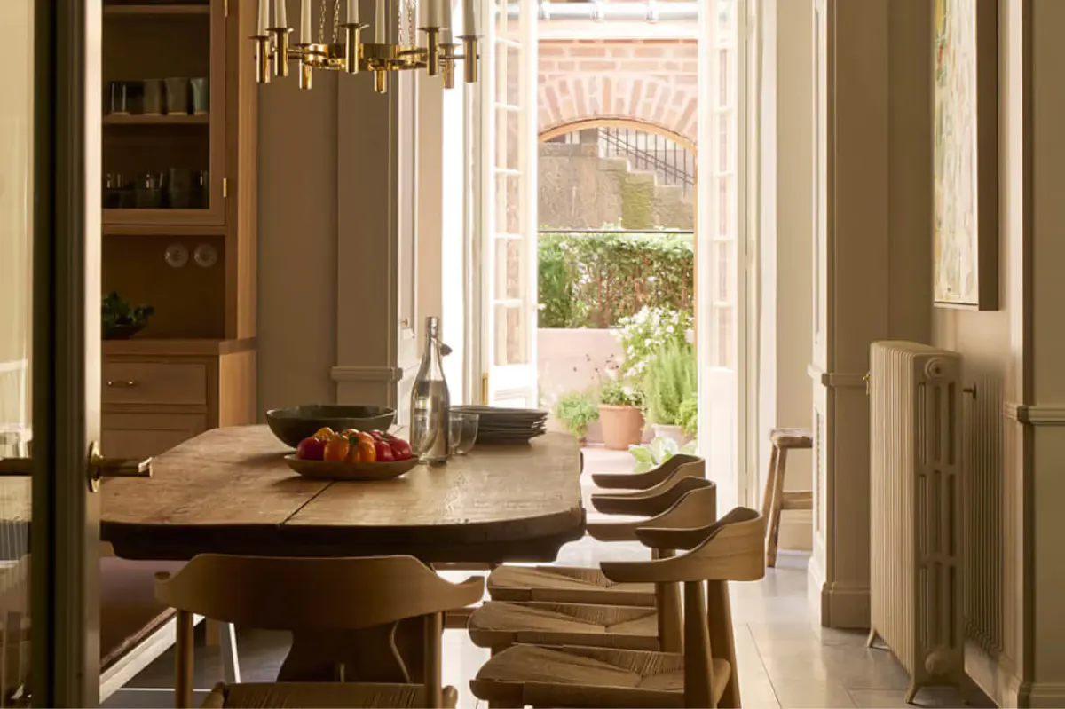 A round table by tall doors with a garden view and pendant lighting, bookshelf visible