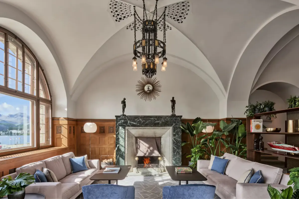 Historic lobby with arched ceiling, ornate chandelier, fireplace, and blue seating accents