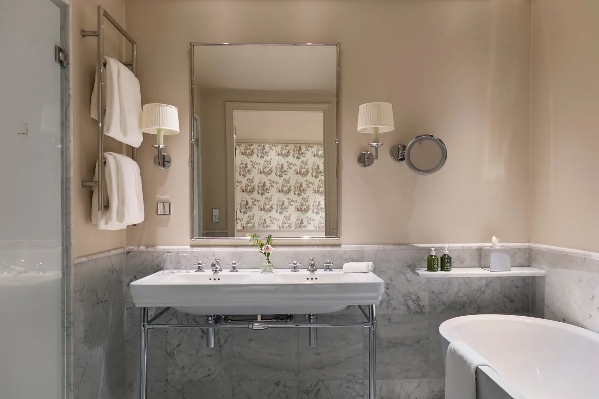 Marble bathroom with vessel sink, brass fixtures, and vintage-style mirror