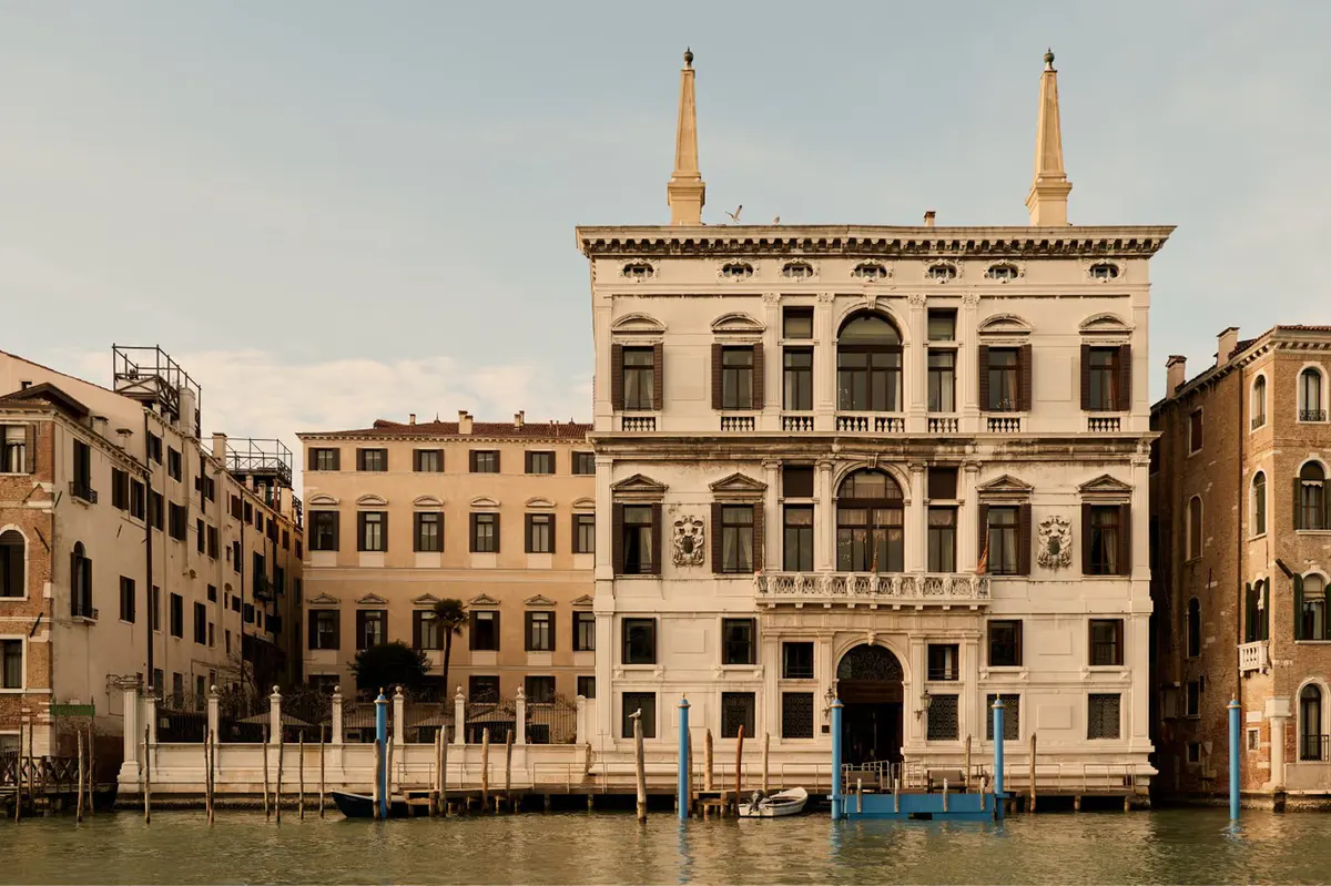 A cream-colored Baroque palazzo facade on the Grand Canal with classical columns and symmetrical windows