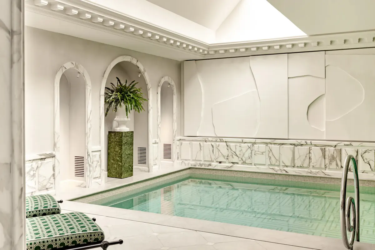 Indoor spa pool with blue water, arched alcoves, and marble cabinetry