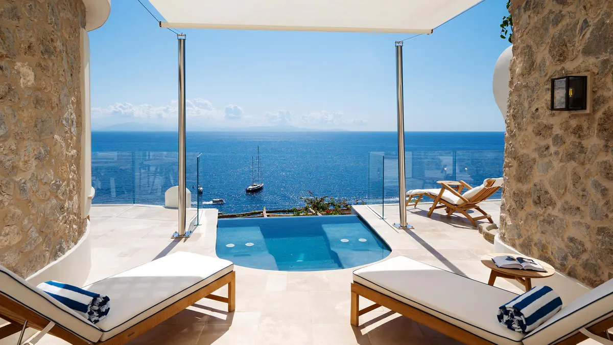 Private suite with plunge pool overlooking the sea, furnished with wood loungers