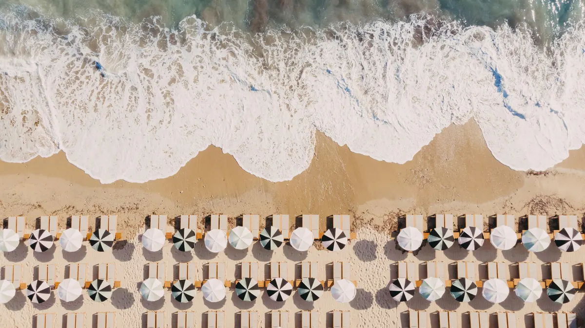 Aerial view of beach loungers arranged in rows above Mediterranean waves
