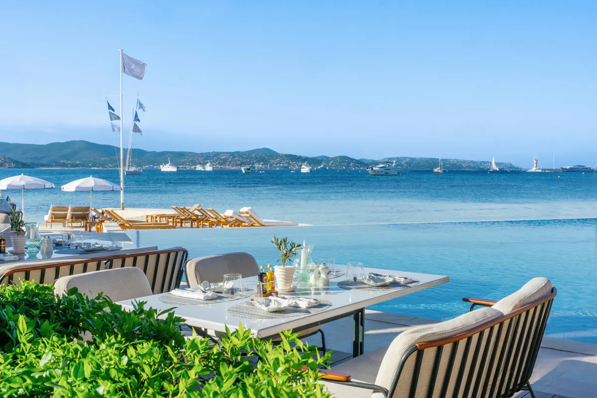 Outdoor dining table with sea views and anchored boats beyond