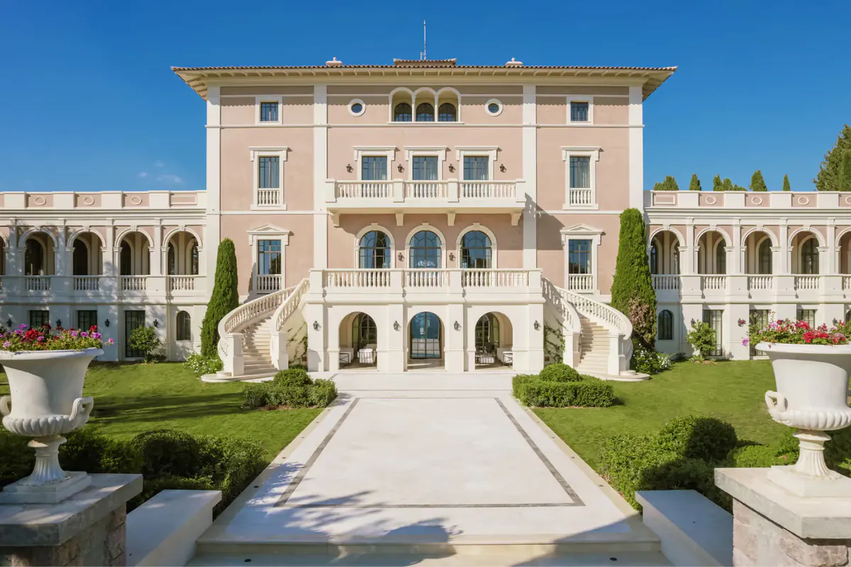 Classical château façade with symmetrical columns, arched openings, and formal garden approach