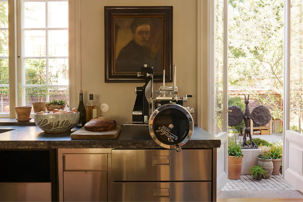 A desk with a wooden top near windows with classical artwork and garden views