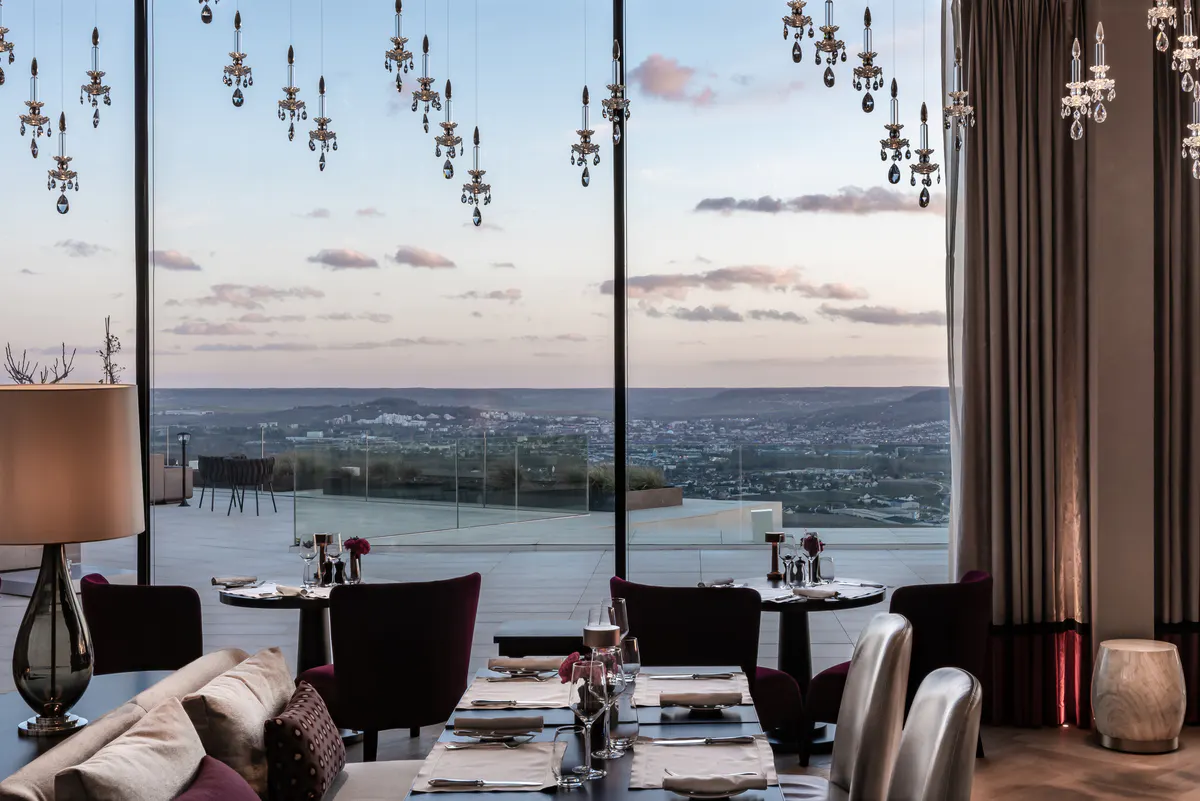 Fine dining table setting with valley landscape stretching to horizon beyond floor-to-ceiling windows