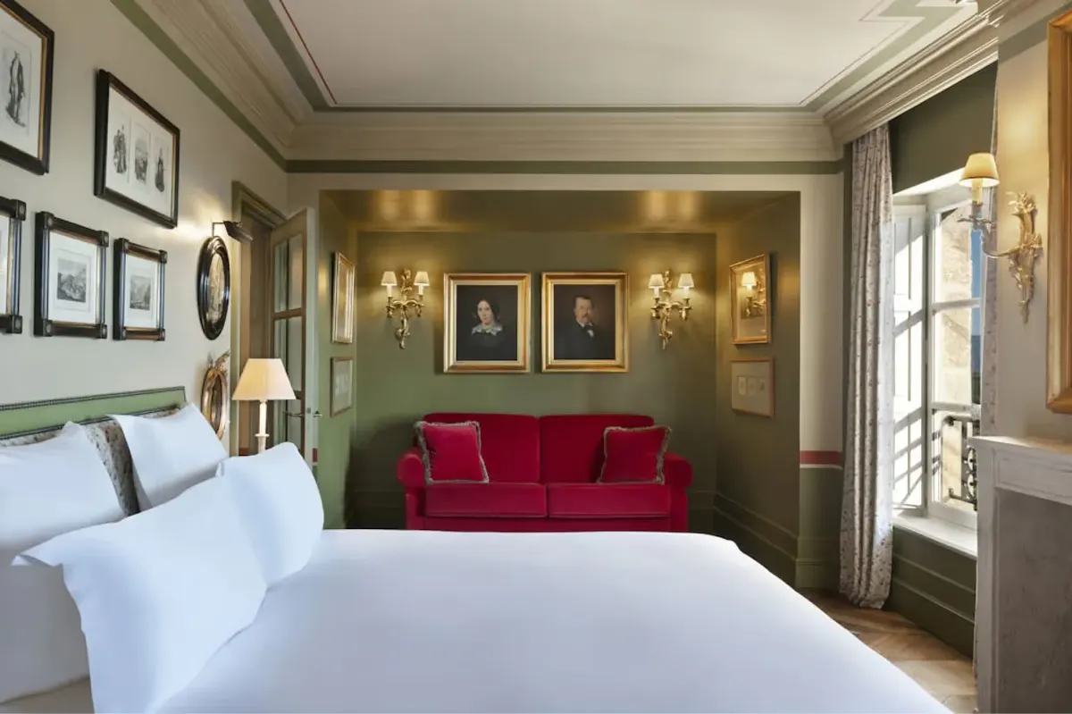 Suite with sage green accent wall, red velvet seating, and terrace access