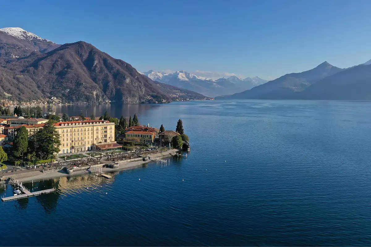 Aerial view of the hotel, pool, and lake with mountains in the distance