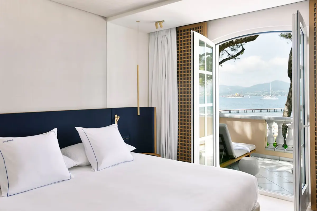 Bedroom with dark headboard, white linens, and sea access door