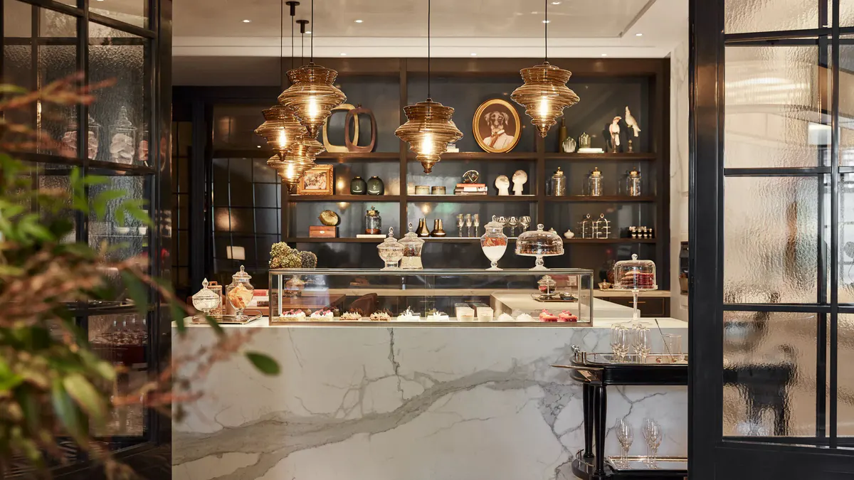 A bar counter with gold pendant lighting, glass display cabinets, and back-lit shelving