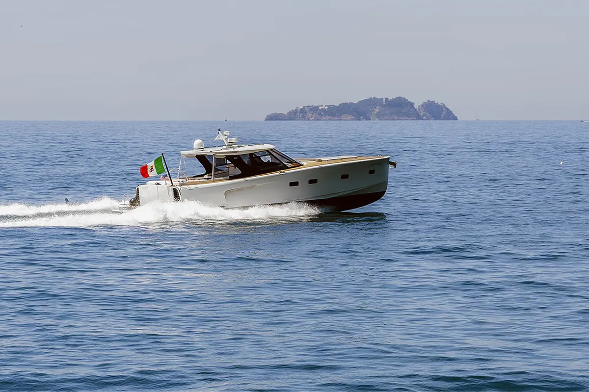 Motorboat on blue water heading toward distant cliffs and islands under clear sky