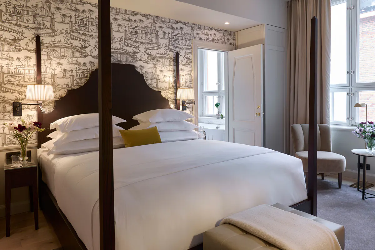 Guest room with brick accent wall, draped windows, and four-poster bed