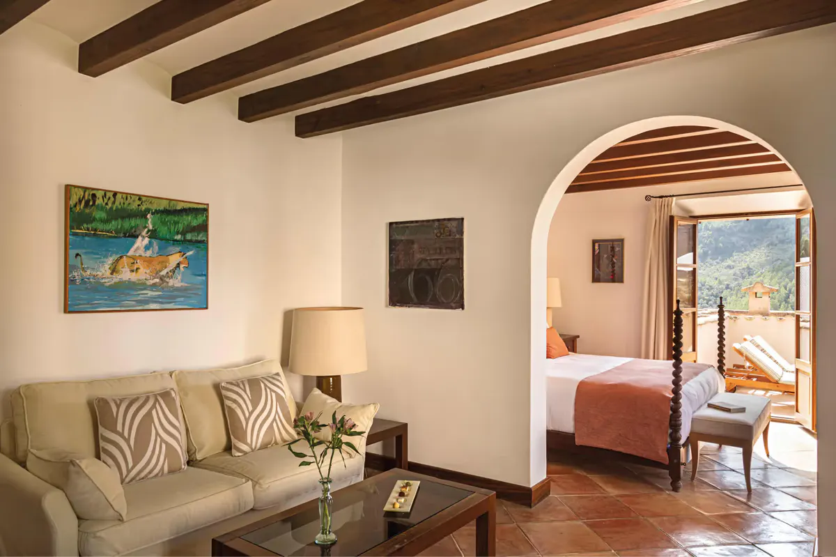 Suite living room with arched stone doorway, upholstered seating, and view to landscape beyond