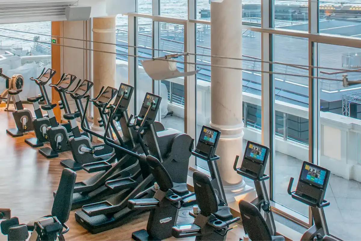 Fitness studio with stationary bikes facing floor-to-ceiling windows over water