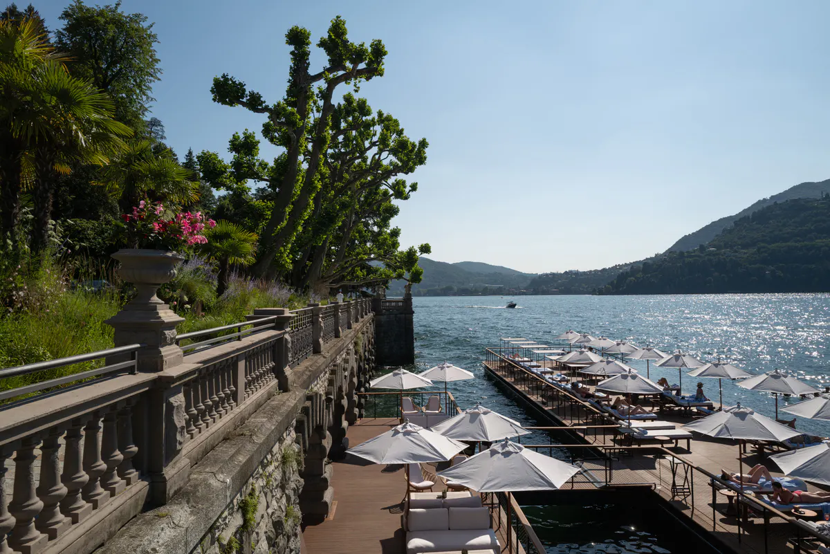 Water’s edge with manicured shrubs, lake access platforms, and distant mountains
