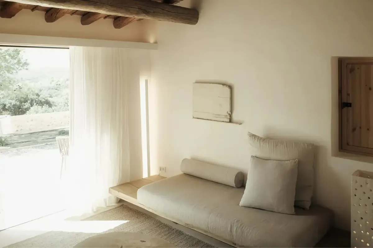 Calm residential alcove with daybed, cushions, and tall window providing soft natural light and garden view