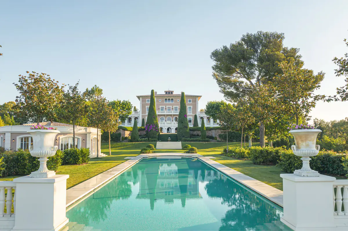 Rectangular lap pool with stone decking, cypress trees, and sea horizon beyond