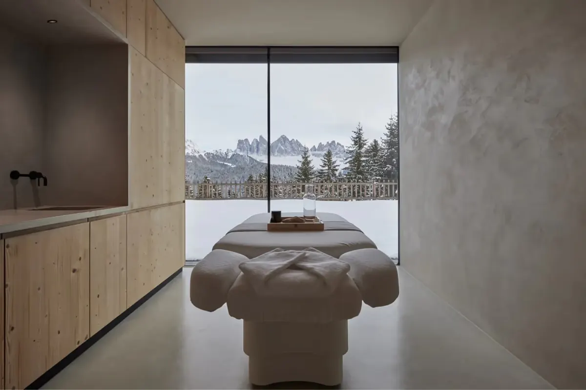A meditation spa room with a sculptural cushioned bench centered by a window overlooking mountains