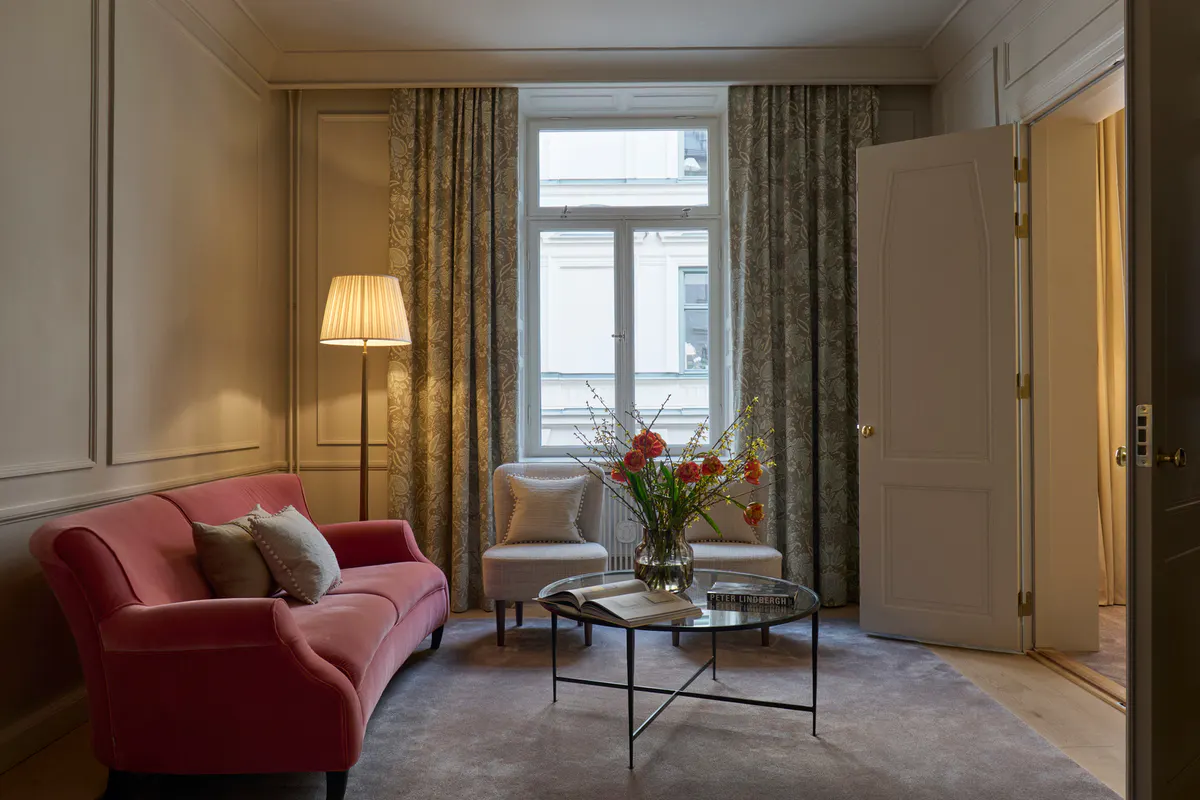 Suite with burgundy seating, city views, and separation between sleeping and living areas