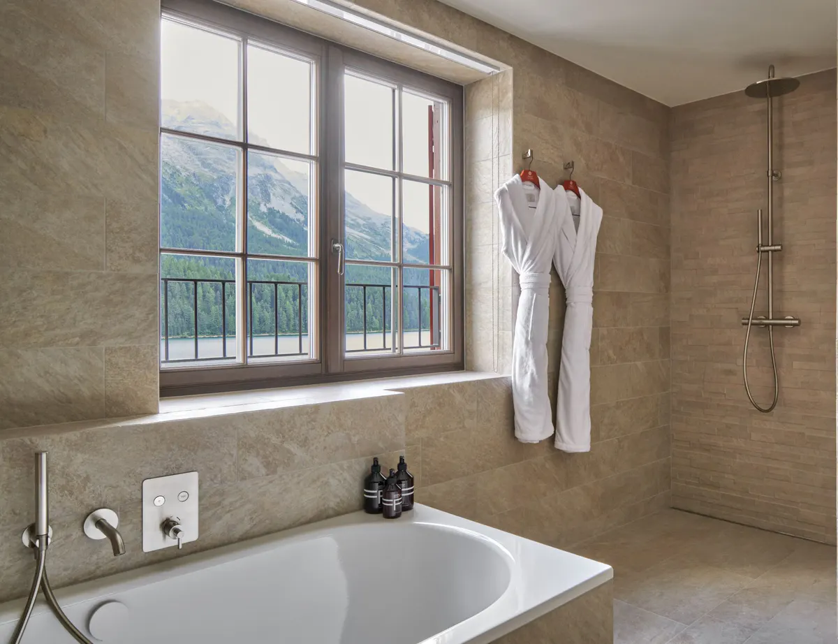 Marble bathroom with stone walls, windows, and modern fixtures against mountain backdrop