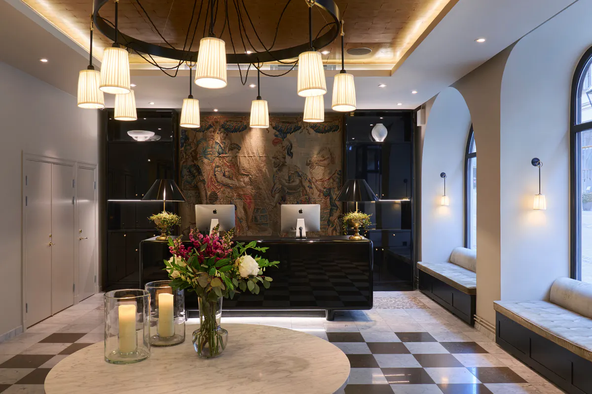 Light-filled lobby with dark accent wall, brass fixtures, and geometric floor pattern