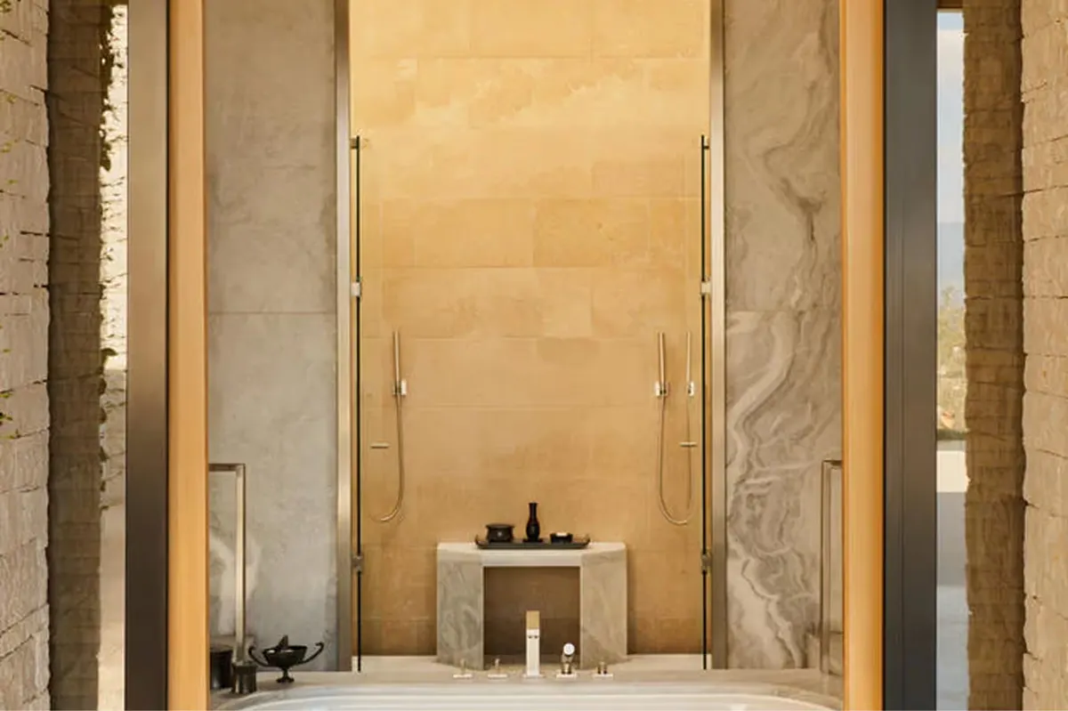 Minimalist spa bathroom with bathtub facing stone walls and natural light