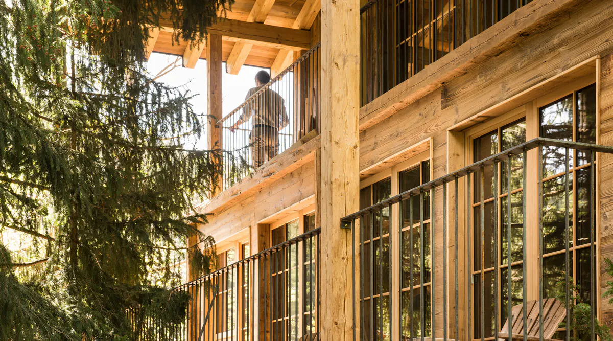Wooden building exterior with balconies and railing details among greenery