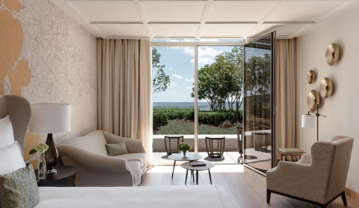 Suite interior with neutral palette, layered seating, and glass doors to a private terrace
