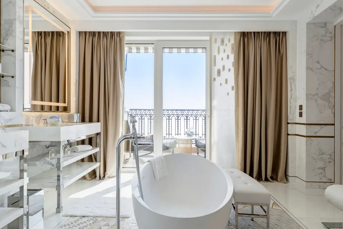 Marble bathroom with soaking tub and balcony overlooking Mediterranean landscape