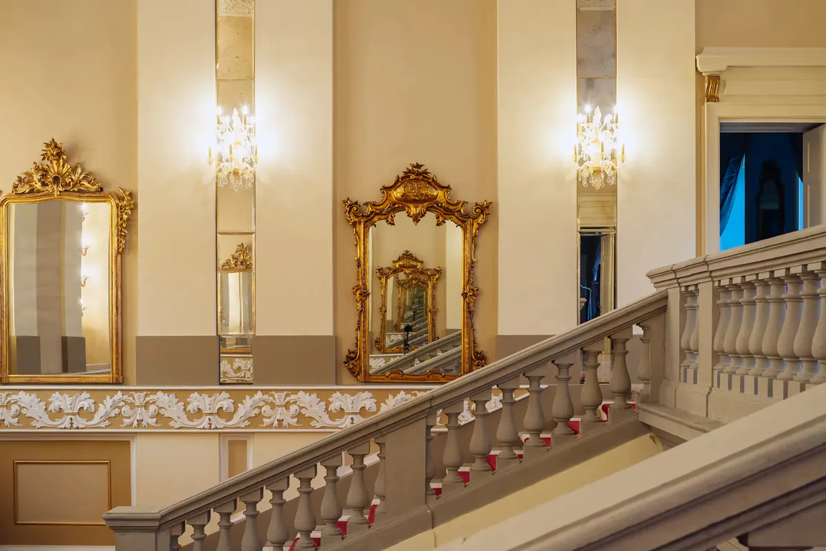 A foyer with marble staircase, gold railings, and Renaissance architectural details