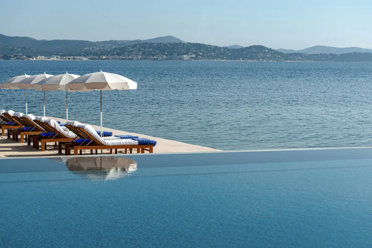 Beachfront with umbrellas and loungers in shallow turquoise water