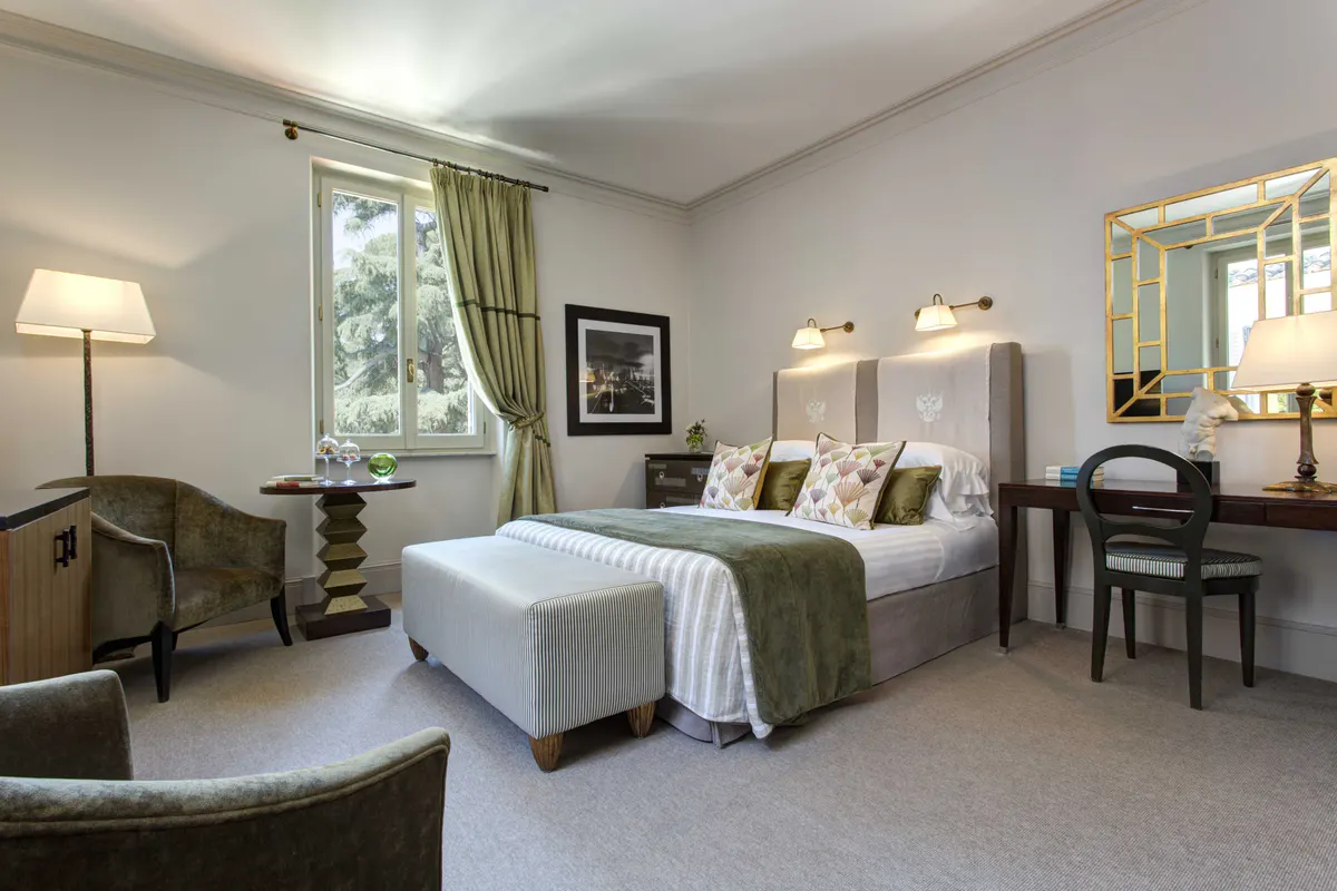 Bedroom with white bedding, green accents, and furnishings with garden windows