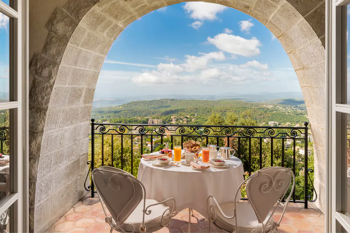 Arched stone terrace with table set for intimate dinner overlooking valley