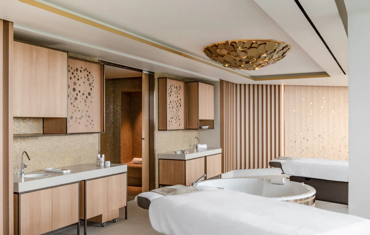 Spa bathroom with freestanding tub, natural wood vanity, and soft lighting