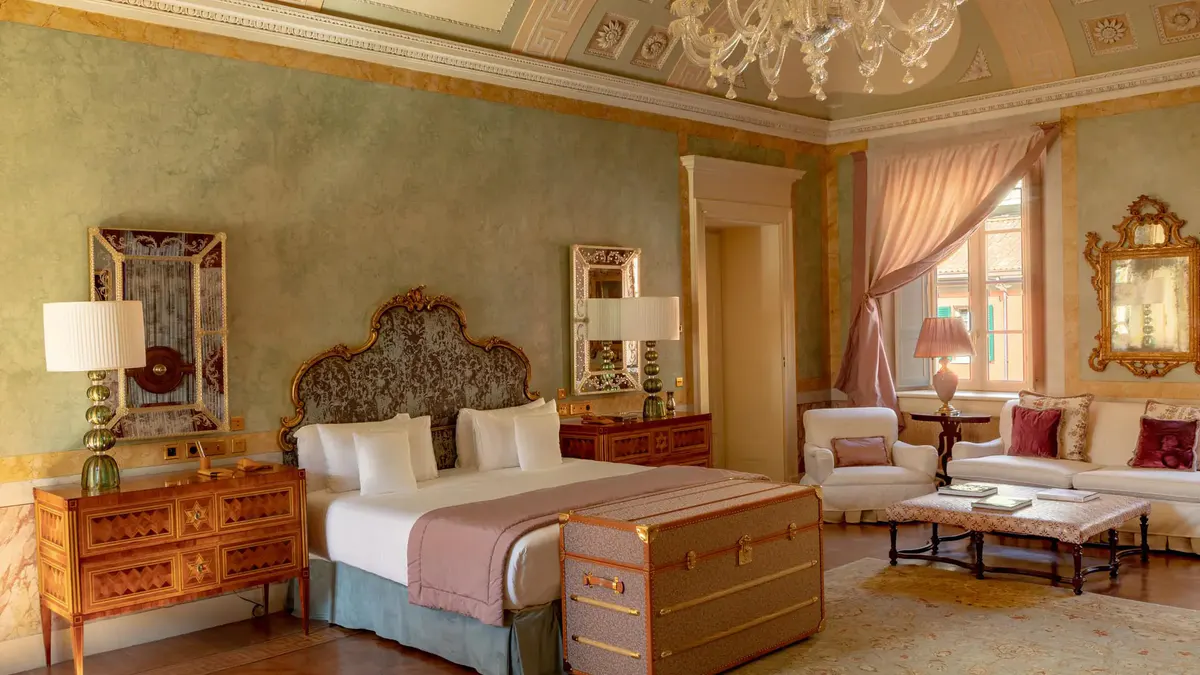 A bedroom with rose ceiling, wood furniture, and gold fabric canopy curtains