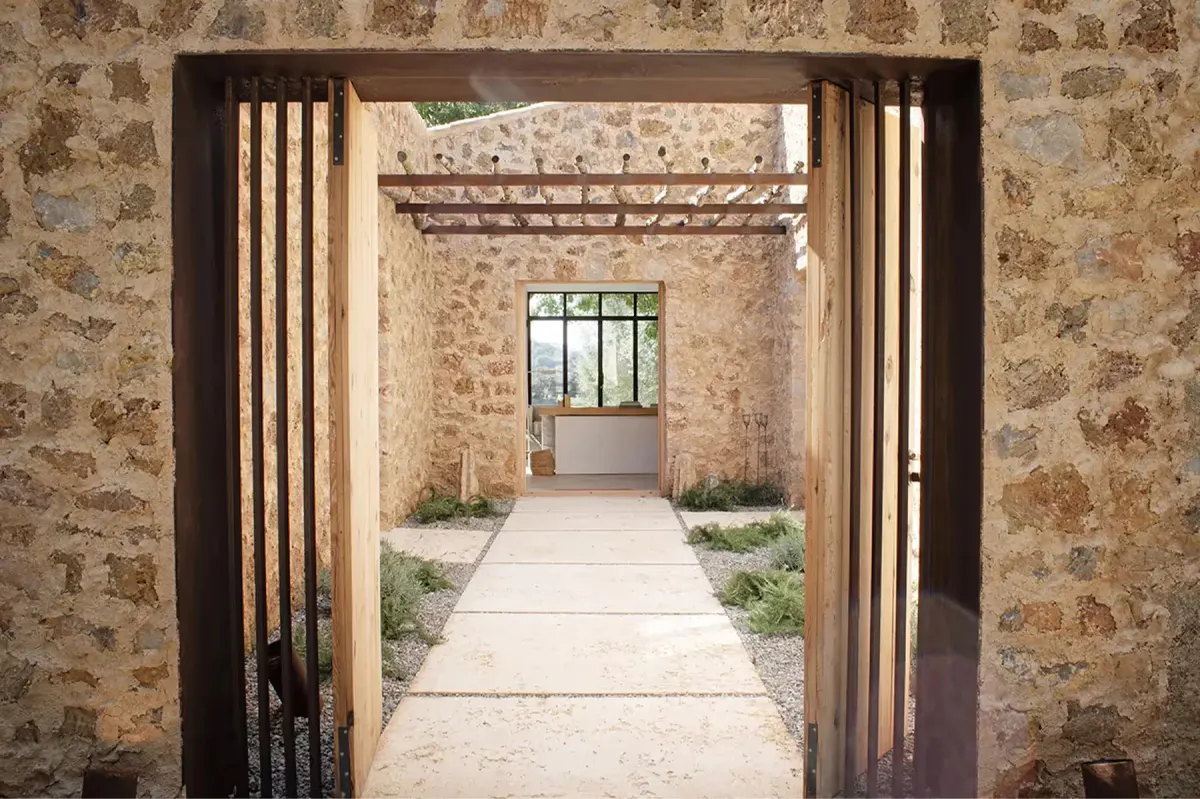 Passageway through stone walls with wooden doors and natural light spilling across floor