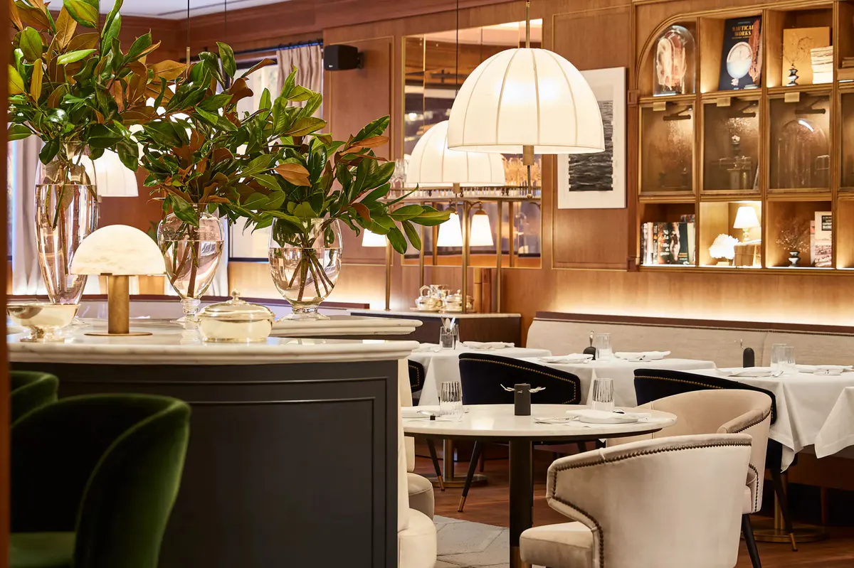 A restaurant with wood paneling, upholstered chairs, and warm ambient lighting
