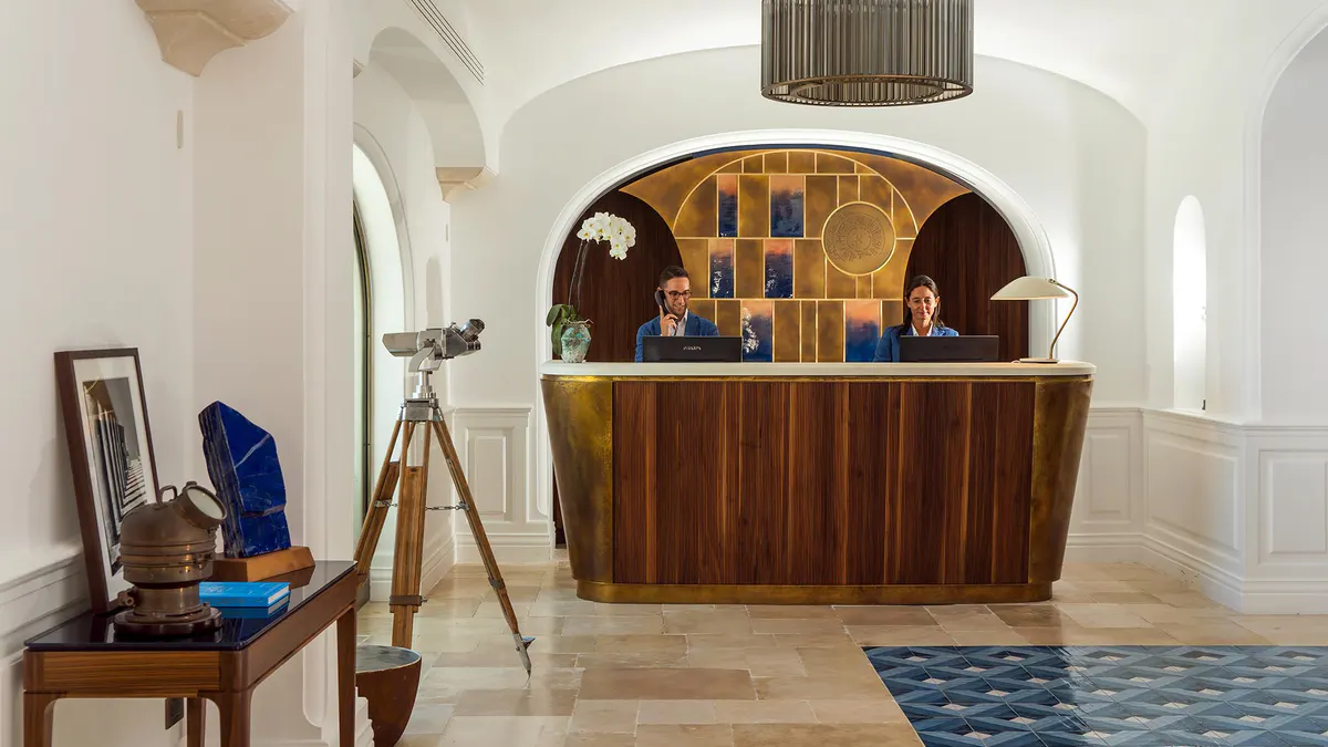 Reception desk in curved stone alcove with wooden cabinetry in whitewashed interior