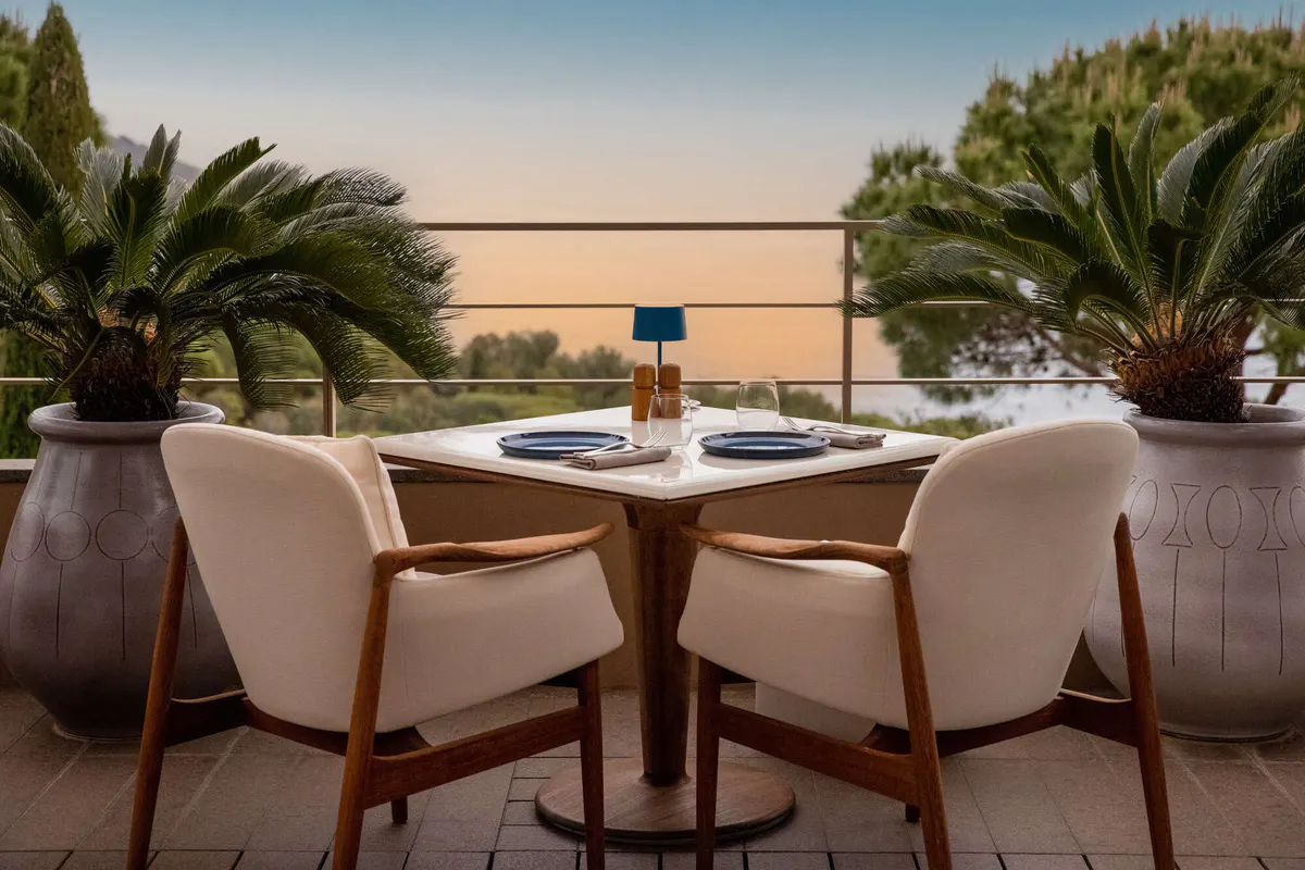 Two white chairs at a round table overlooking the sea